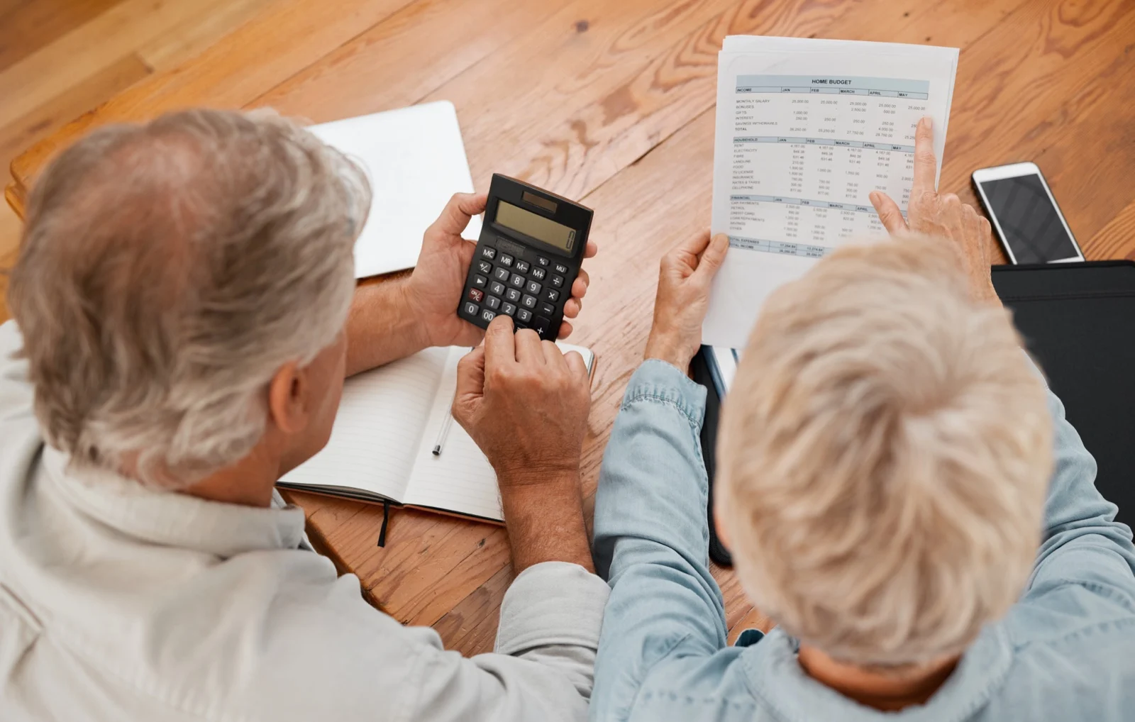 Un couple de seniors calculant son budget avec une calculatrice et des relevés financiers
