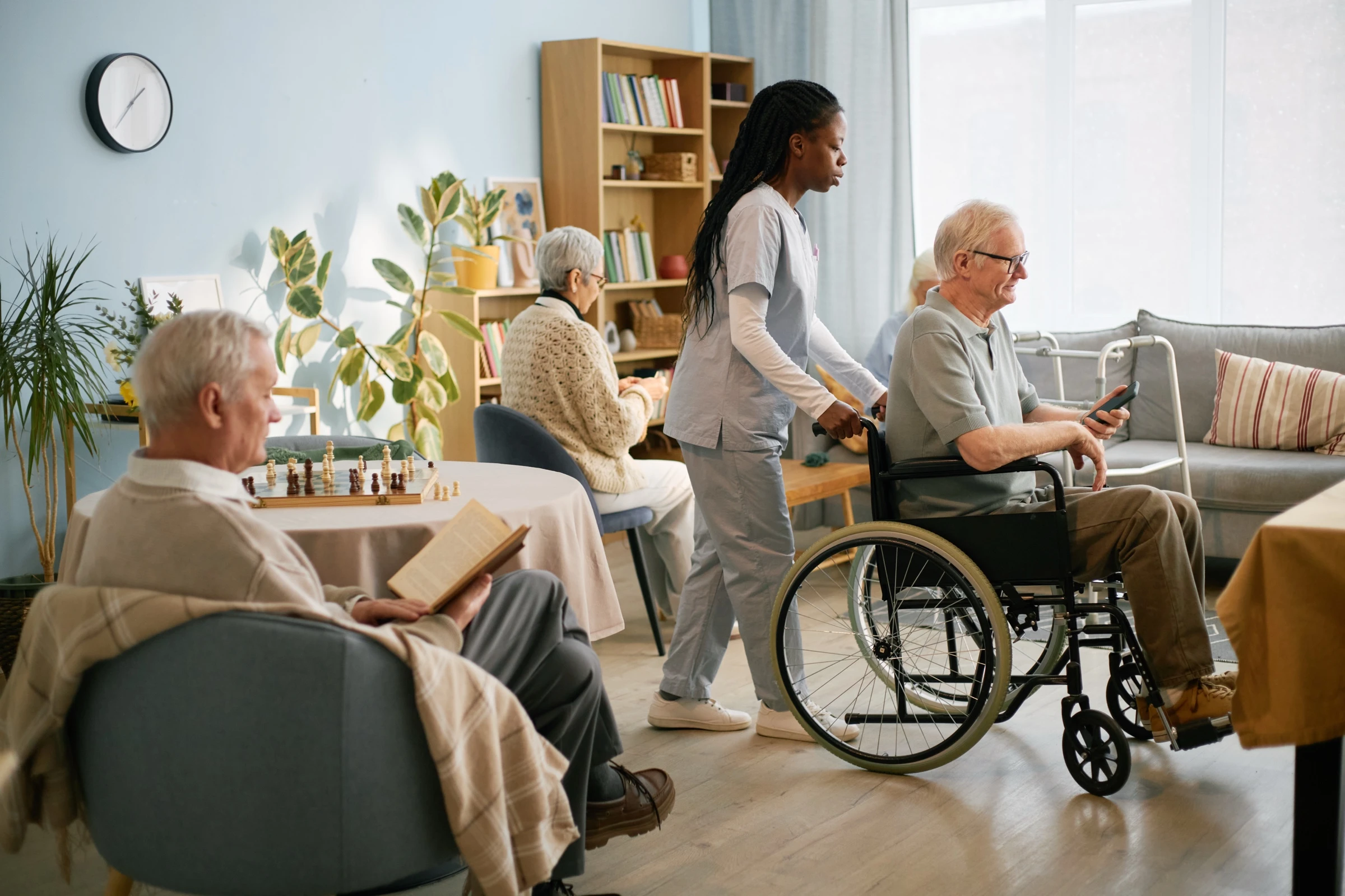 Soignante en unité protégée d'EHPAD accompagne avec attention un résident âgé en fauteuil roulant, geste de soin bienveillant et lien humain quotidien