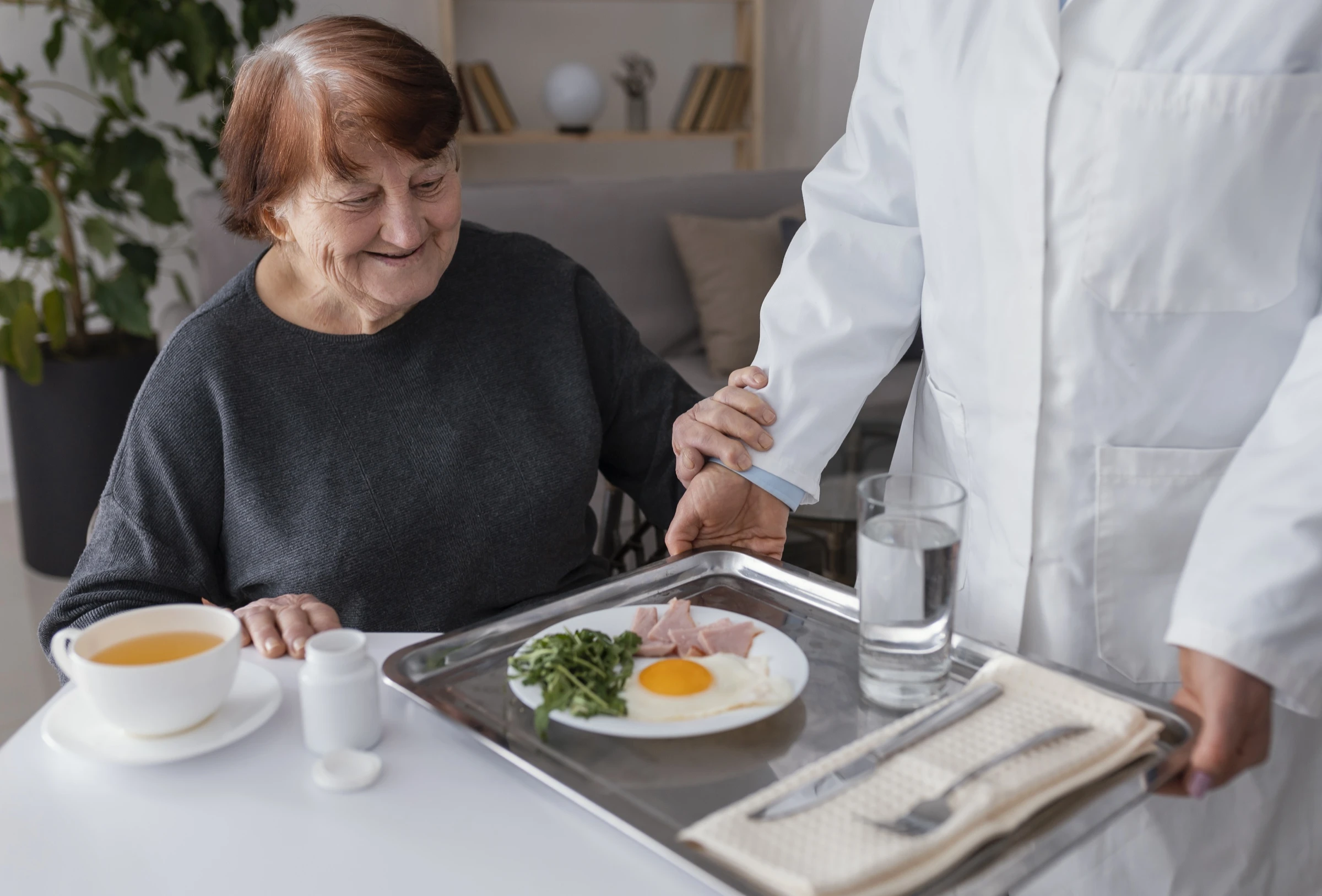 Femme âgée résidente d'EHPAD prend son petit-déjeuner en gros plan, moment quotidien rythme de vie structuré