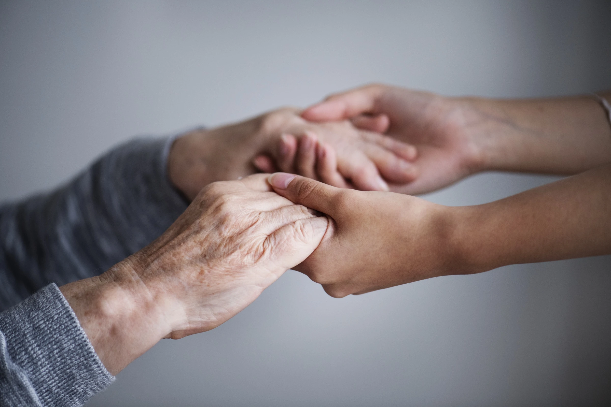 Mains d'un aidant familial soutenant celles d'un proche âgé, geste de réconfort lors de l'évaluation GIR et des démarches AGGIR