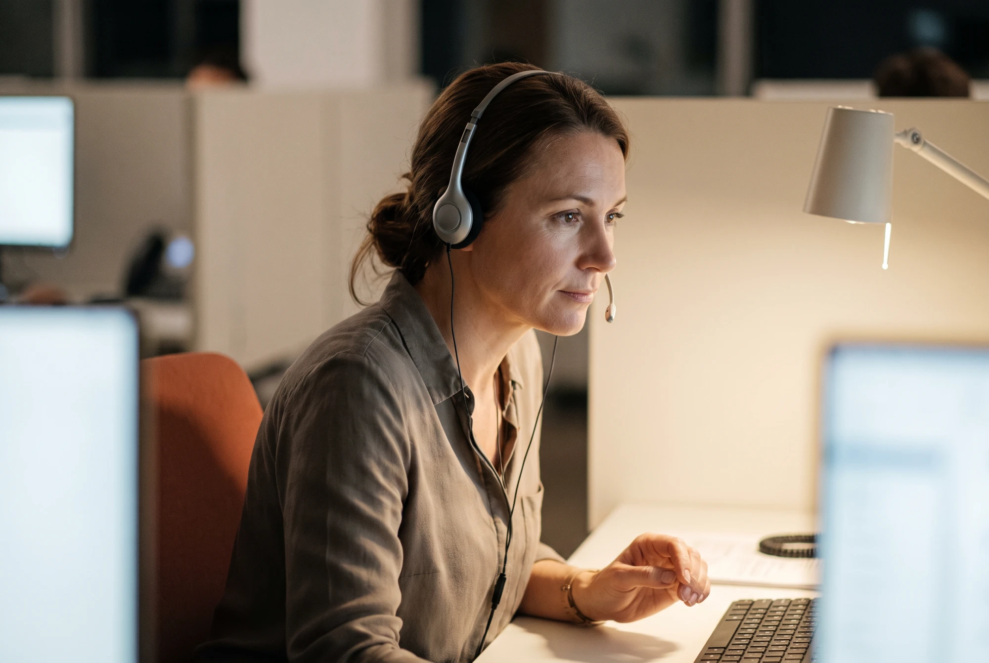 Chargée d'écoute d'un centre de téléassistance, casque sur les oreilles, répondant à un appel la nuit.
